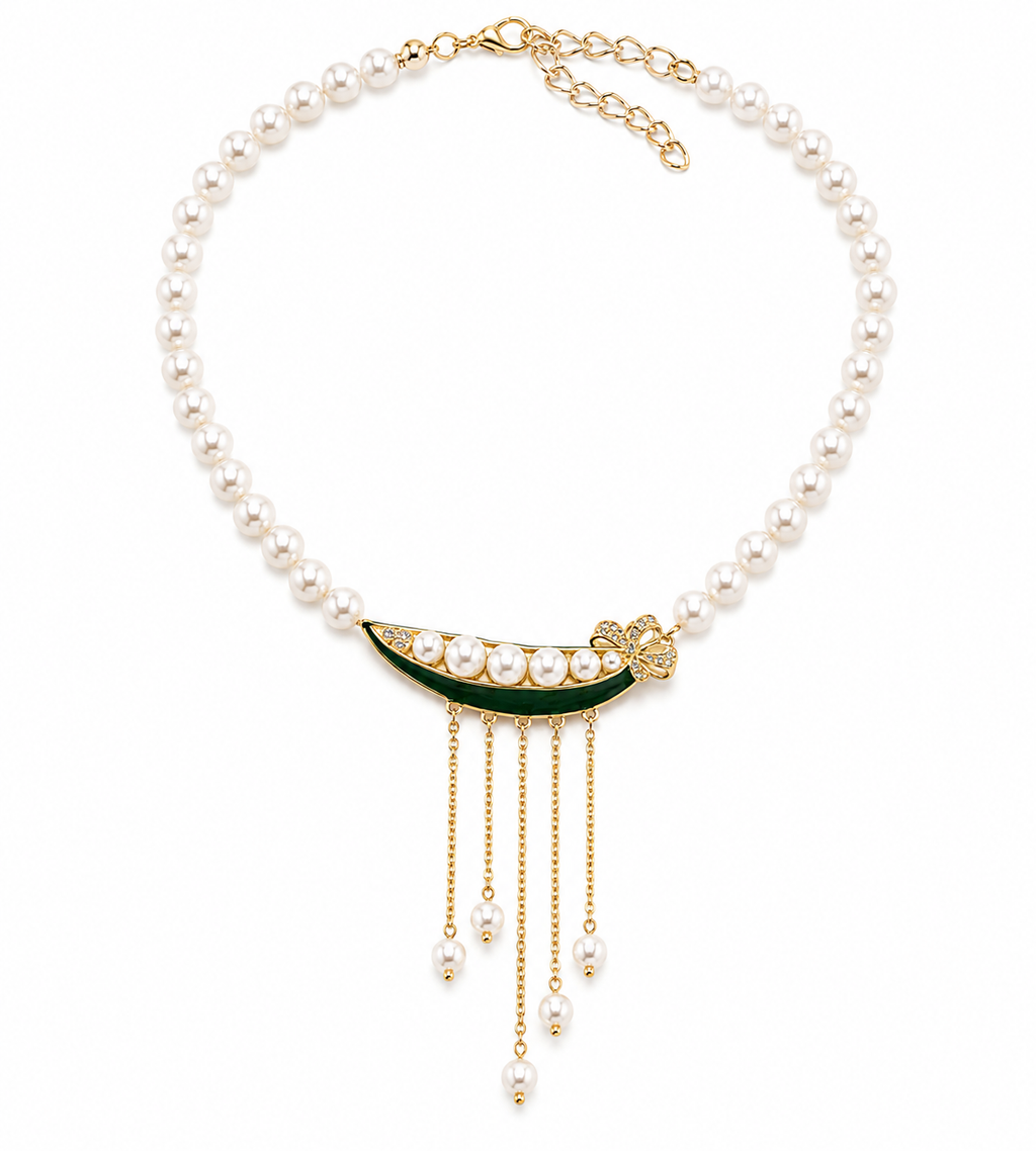 A pearl necklace with a gold crescent moon pendant decorated with green enamel and small pearls, featuring dangling gold chains with pearl beads.