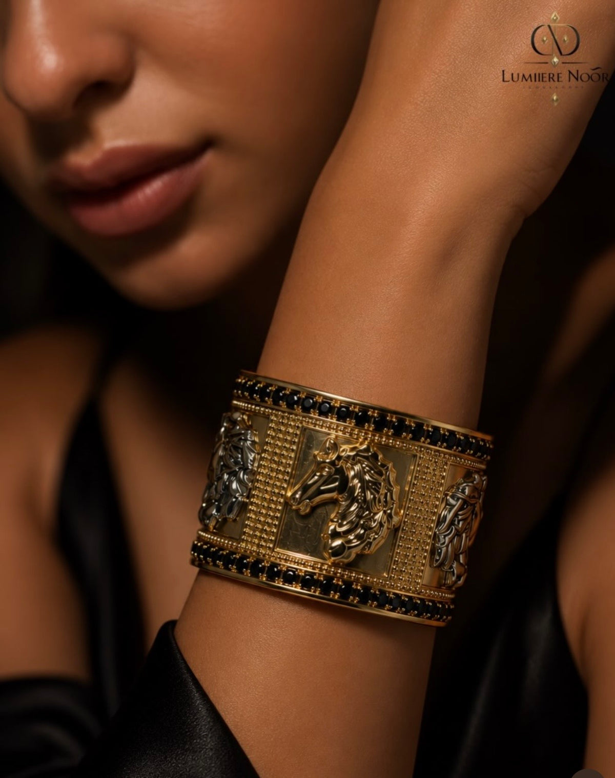 A close-up lifestyle shot of a woman's wrist wearing an ornate gold cuff bracelet with horse motifs and dark blue gemstone accents. The brand logo 'LUMIÈRE NOOR' is visible in the top right corner.