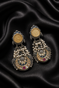 A pair of ornate gold-tone crescent-shaped drop earrings with pearl clusters and blue and pink stone accents, displayed on draped black satin fabric.