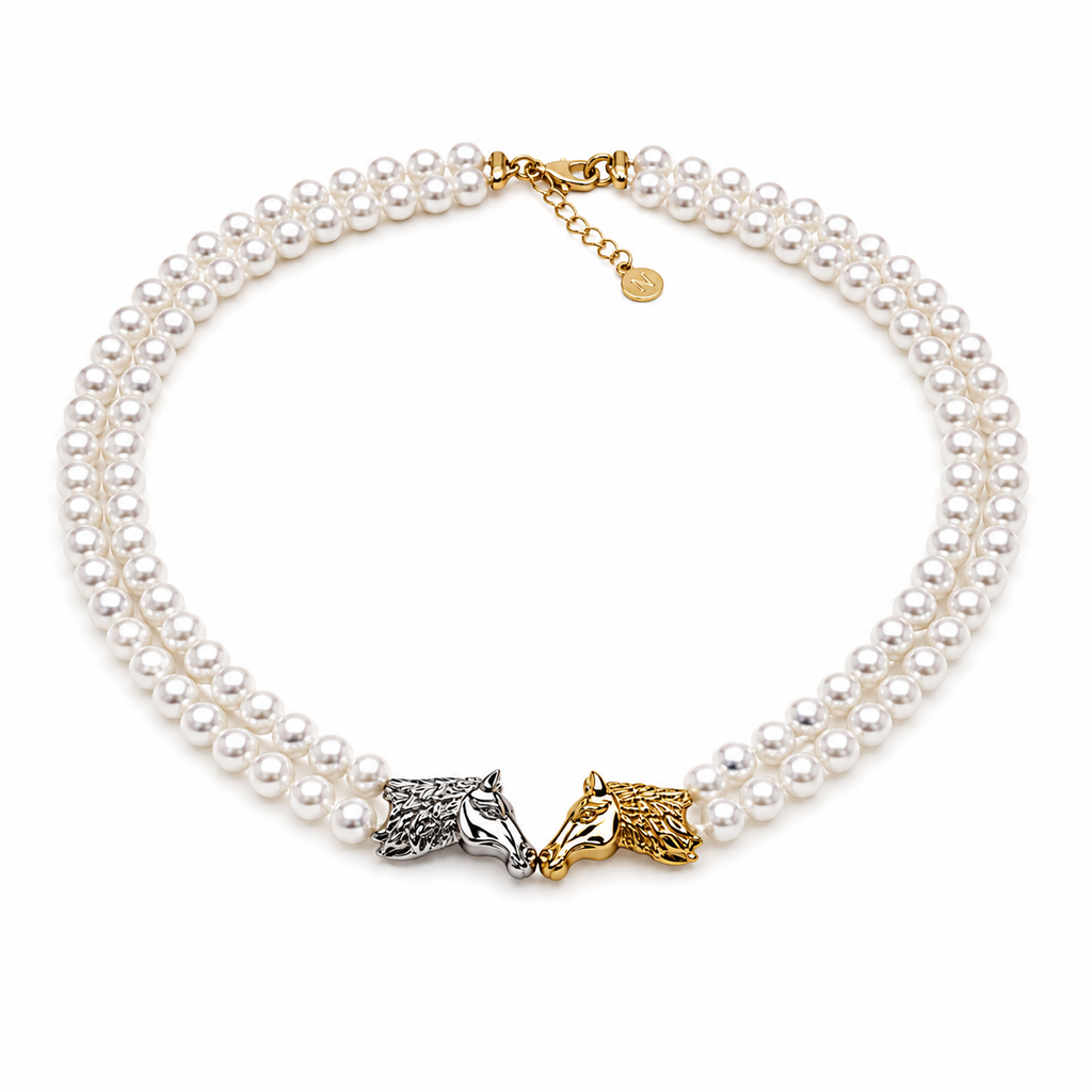 A double-strand pearl necklace with a gold clasp and two horse head charms, one in silver-tone metal and one in gold-tone metal, displayed on a clean white background.