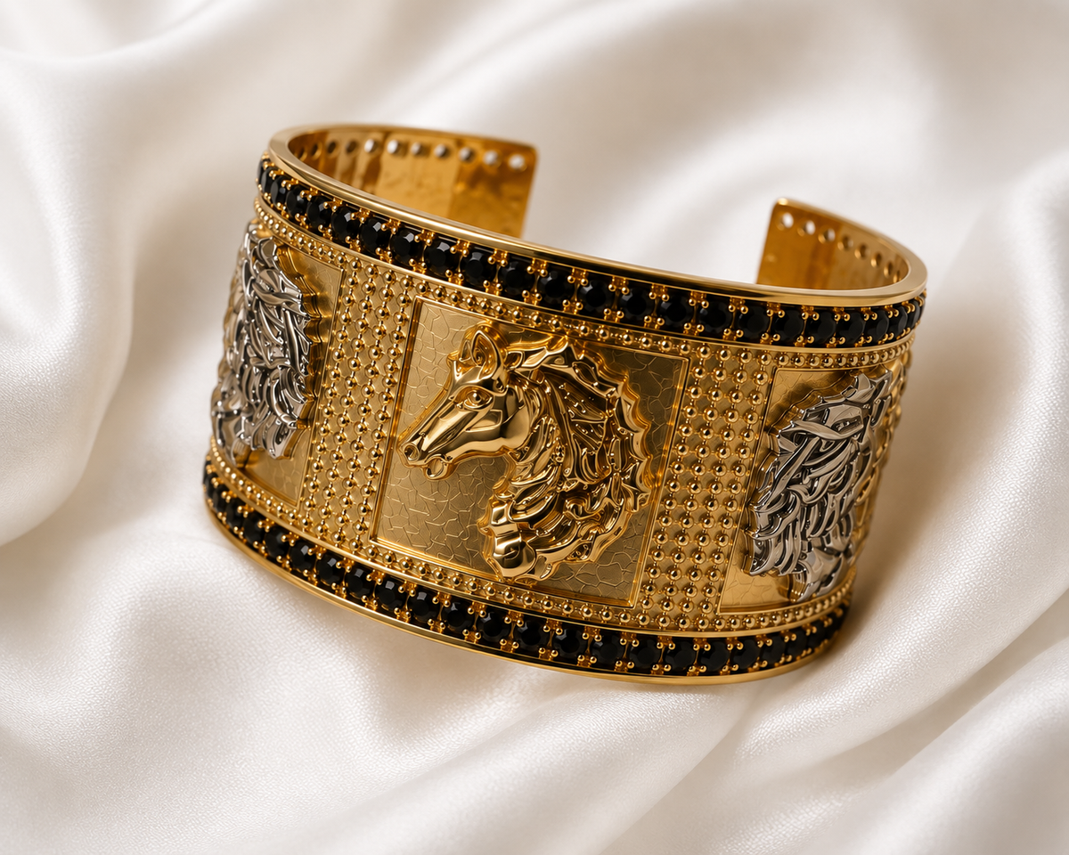 A wide gold cuff bracelet with raised horse head motifs, bordered by rows of small black stones, photographed on draped white satin fabric.